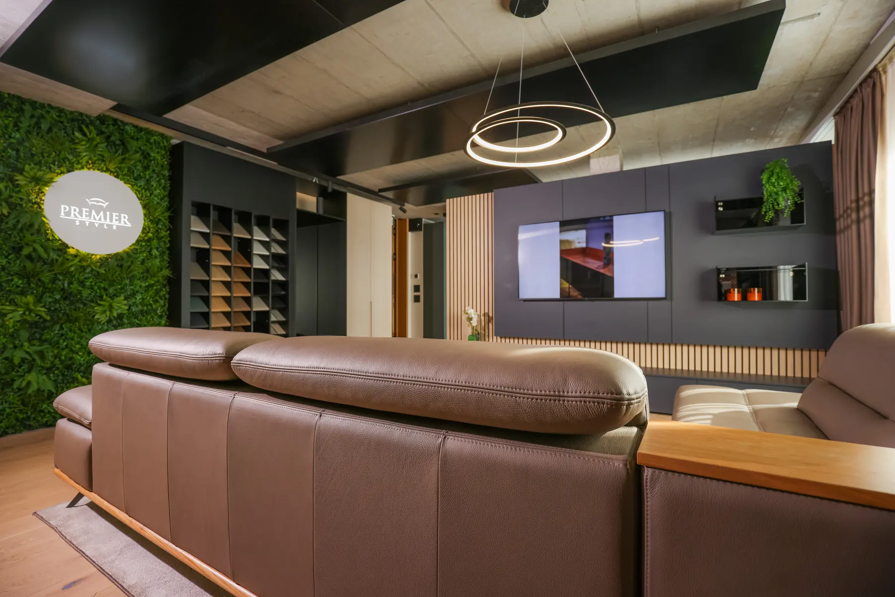 Showroom der Premier Style AG in Küssnacht am Rigi mit Sofa, Wandmöbel und Logo an der Pflanzenwand